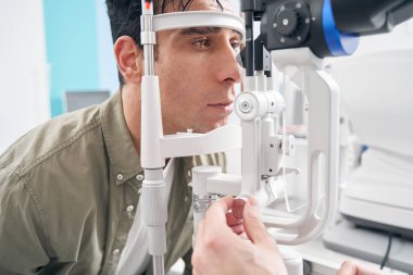 Kesik lamba kullanan erkek göz muayenesi yaptırıyor.