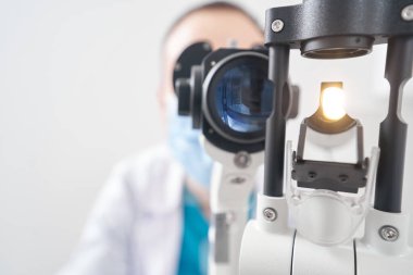 Hastanede biyomikroskop kullanan profesyonel erkek doktor.