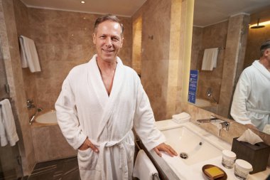 Rahat banyo bornozuyla rahatlamış görünen memnun bir beyefendi.