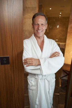 Beyaz cüppeli beyefendi kameraya gülümsüyor.