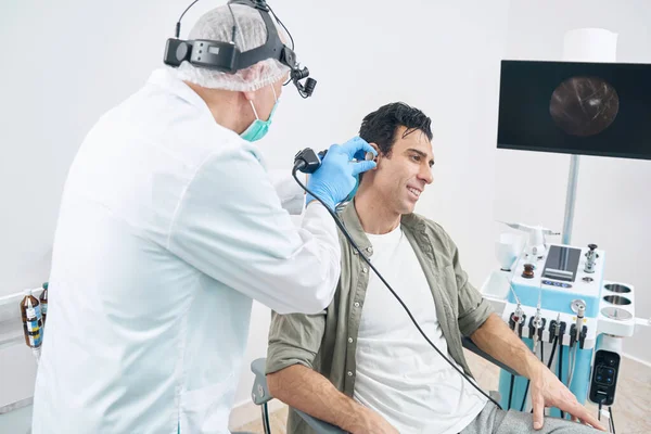 Otorhinolaryngologue examinant un homme avec un instrument médical à l'hôpital — Photo