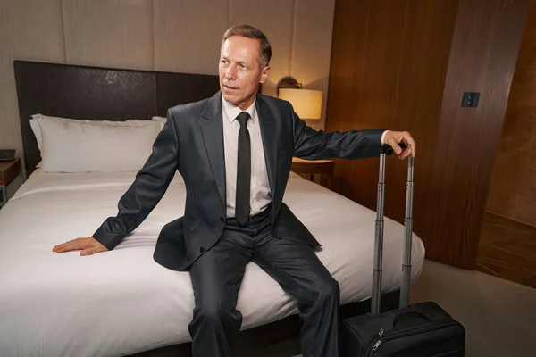 Zdeterminowany przedsiębiorca odpoczywający na łóżku hotelowym po długiej podróży — Zdjęcie stockowe