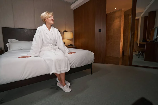 Hermosa mujer alegre en bata de baño relajante en la habitación del hotel — Foto de Stock