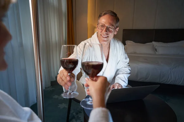 Heyecanlı beyefendi otel odasında şarap kadehini kaldırıyor. — Stok fotoğraf