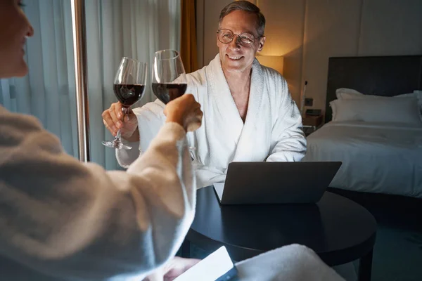 Emocionado caballero bebiendo vino con su pareja en la habitación del hotel — Foto de Stock