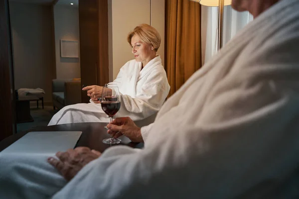 Donna raffreddata che guarda il suo smartphone mentre si rilassa in hotel — Foto Stock