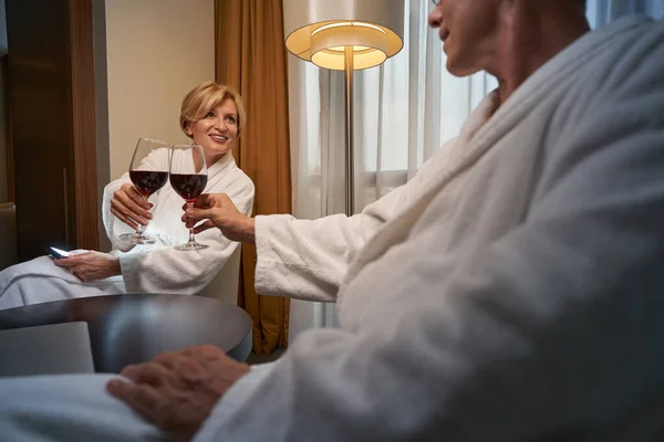 Vzrušená krásná žena pití vína s přítelem v hotelovém pokoji — Stock fotografie