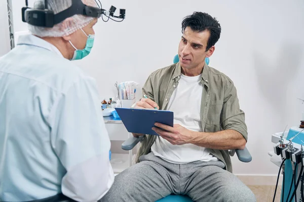 Пацієнт сидить в кабінеті оториноларинголога за попереднім записом — стокове фото