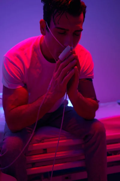 Homem sentado na sala com luz rosa e orando — Fotografia de Stock