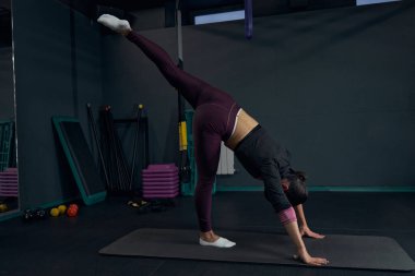 Yoga pozunda duran nazik esmer kadın.