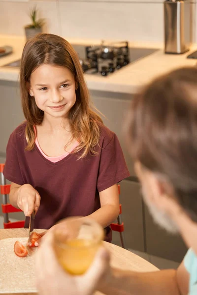 Ragazza che taglia i pomodori in cucina accanto al suo genitore — Foto Stock