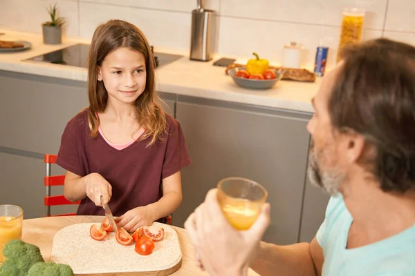 Ragazza adolescente che prepara le verdure accanto a suo padre in cucina — Foto Stock