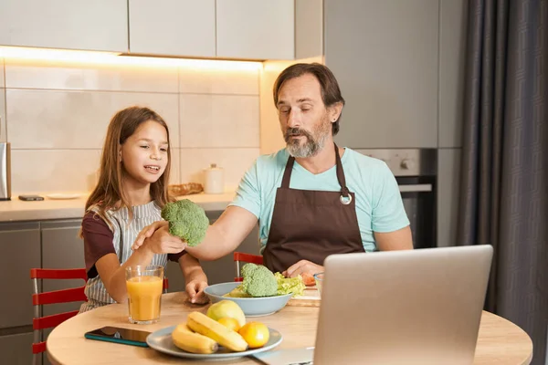 Adolescente che cucina un pasto con un uomo adulto mentre guarda gadget — Foto Stock