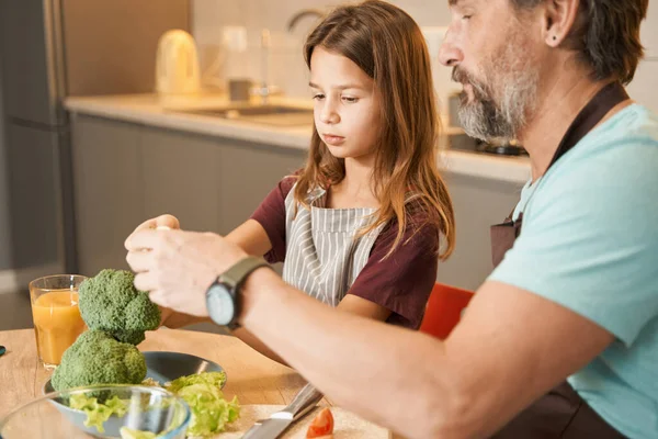 Erwachsener Mann mit Teenager-Mädchen bereitet Gemüse in der Küche zu — Stockfoto
