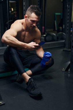 Rahatlamış esmer adam aletin üzerinde gelir mesajları okuyor.