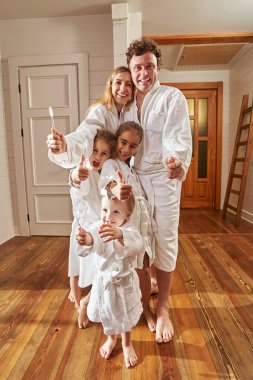 Diş fırçası tutan genç ebeveynlerin ve çocukların portresi