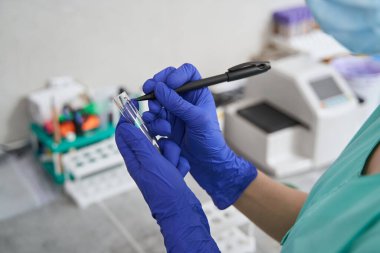 Laboratuvarda şişelere not alan bir kadın.