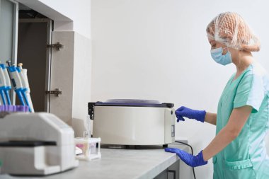 Hastanede santrifüjle tıbbi araştırma yapan bir kadın var.