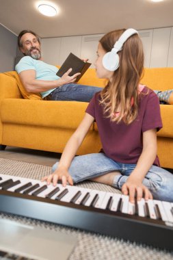 Yerde sentezleyici çalan genç bir erkeğin yanında.