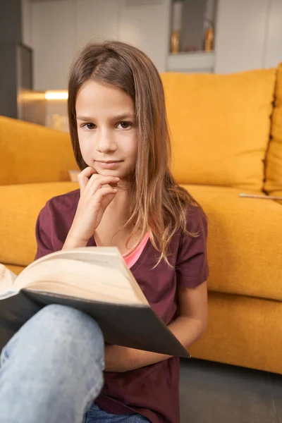 Підліток сидить на підлозі з відкритою книгою — стокове фото