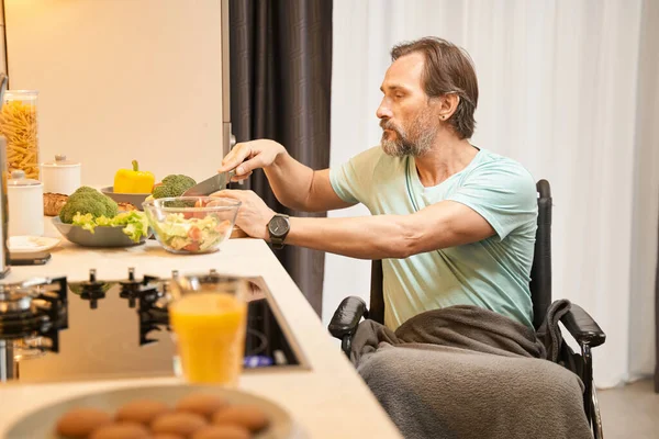 坐在轮椅上的成年人在厨房里切蔬菜 — 图库照片