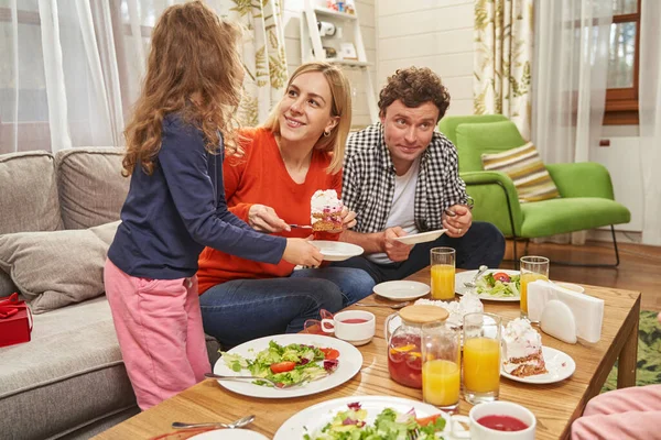 Genitori felici con figlia che mangia a casa — Foto Stock