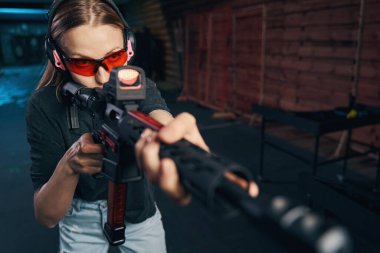 Güvenlik gözlükleri ve kulaklık takan deneyimli keskin nişancı ateşli silah kullanıyor.