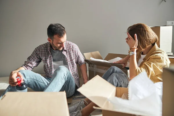 Couple searching for something among open cardboard boxes — Stock Photo, Image