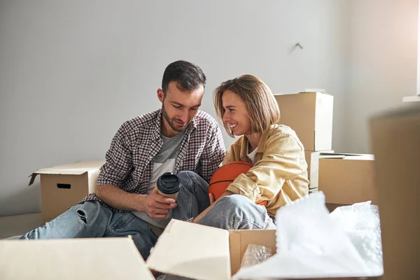 Pareja sentada en el suelo entre cajas desempaquetadas — Foto de Stock