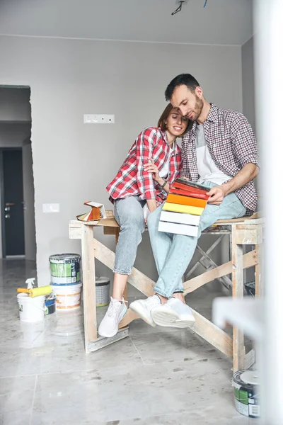 Ung mann og hans smilende kone undersøker byggematerialer – stockfoto