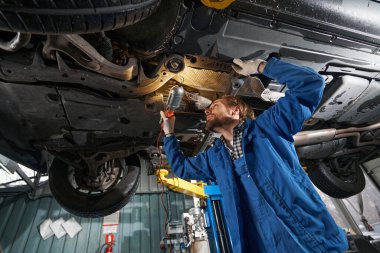 Elinde lamba tutan ve makine kontrolü yapan yetişkin bir adam.
