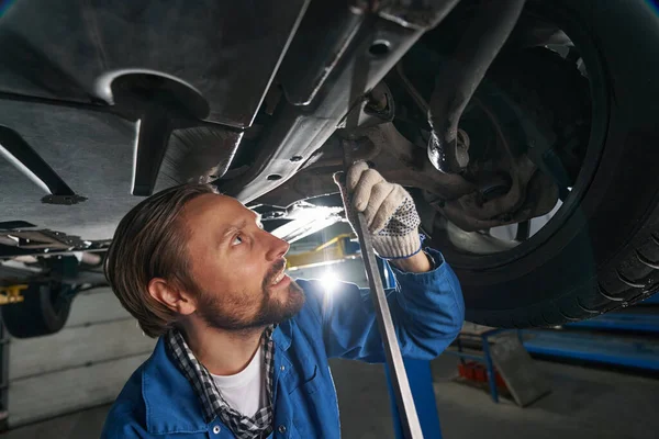 Mann hält Werkzeug in der Hand und repariert Auto an Tankstelle — Stockfoto