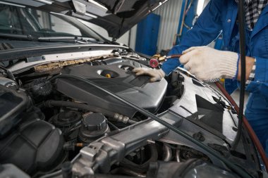 Erkek servis merkezinde çalışıyor ve yağ basıncını kontrol ediyor.