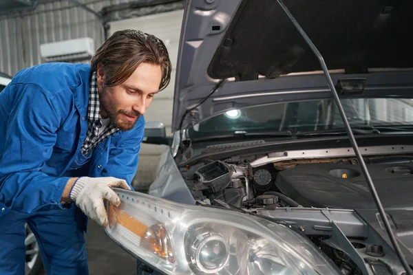 Mann führt Diagnose der Autooptik in der Werkstatt durch — Stockfoto