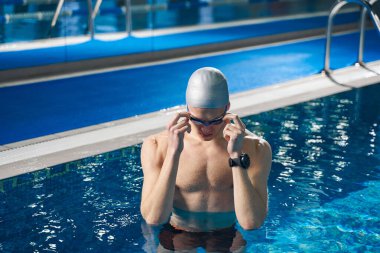 Güçlü erkek havuzda duruyor ve antrenmana hazırlanıyor.