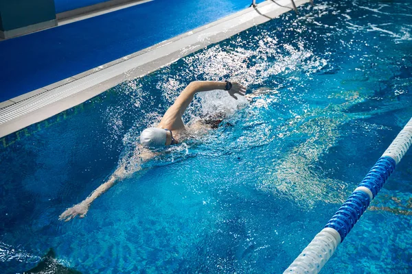 Athletic man swimming in pool, night workout
