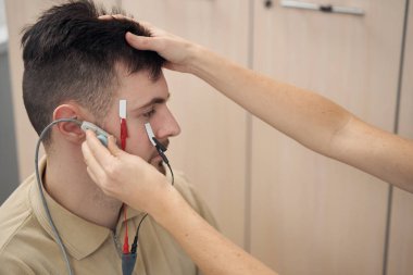 Genç adam elektromiyografi için modern kliniği ziyaret ediyor.