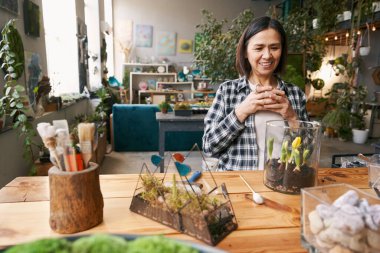 Kadın dinleniyor, çay içiyor ve çiçeklere bakıyor.