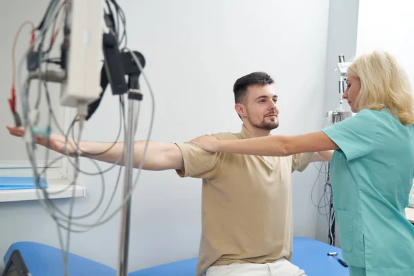 Glimlachende man bewegende armen in neuroloog kantoor — Stockfoto