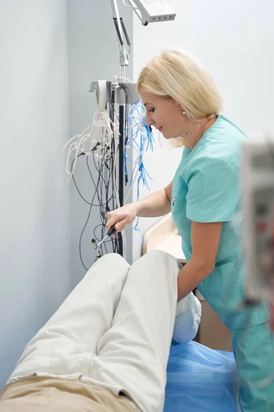 Donna in uniforme medica esaminando paziente maschile — Foto Stock
