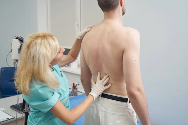 Mujer médico examinando la columna vertebral del hombre en el consultorio — Foto de Stock