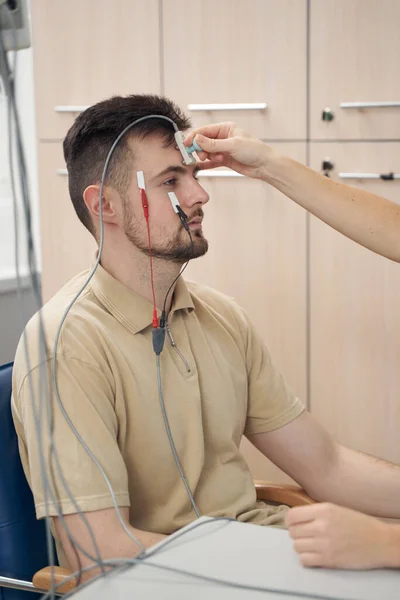 Hombre joven durante el procedimiento de electromiografía en la clínica — Foto de Stock