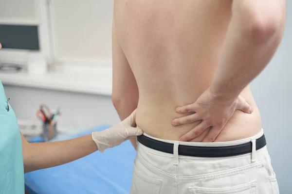 Uomo che si lamenta del dolore alla schiena dal medico — Foto Stock