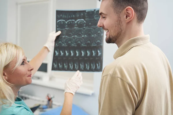 Hombre feliz discutiendo rayos X con doctora — Foto de Stock