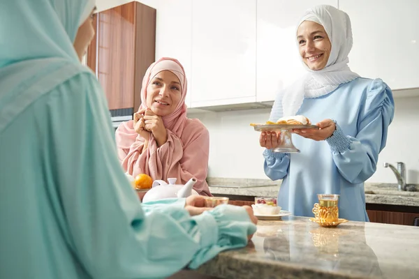 친절 한 모슬렘 여인 이 맛있는 과자를 제공하고 웃는다 — 스톡 사진