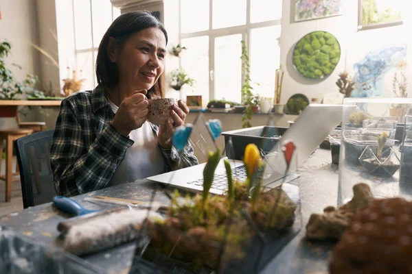 Glimlachende vrouw aan het werk in workshop op laptop — Stockfoto