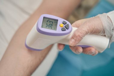 Doktor klinikte hasta sıcaklığını ölçüyor.