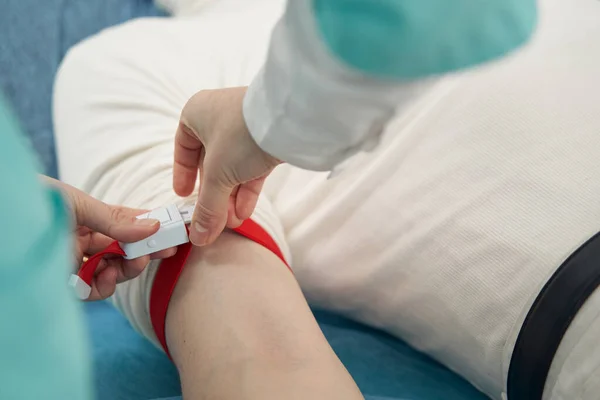 Enfermera poniendo torniquete en brazo masculino en el hospital — Foto de Stock