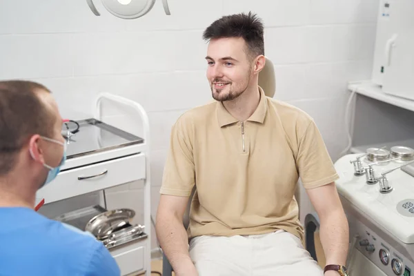 Усміхнений чоловік розмовляє з лікарем в офісі — стокове фото
