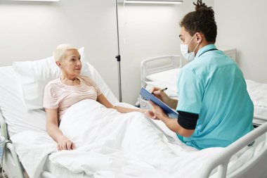 Sıhhiye, serum tedavisi sırasında hastadan not alıyor.